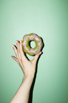 Hand holding delicious sweet green pink matcha strawberry glazed donut
