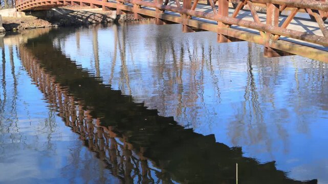 Reflection of an iron bridge in the flowing waters of the Delaware and Raritan Canal within a state park in New Jersey, USA.