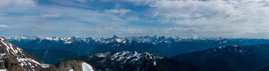 Fototapeta premium Panoramic Snow-Capped Mountain Range With Rugged Peaks and Dramatic Sky in British Columbia, Canada