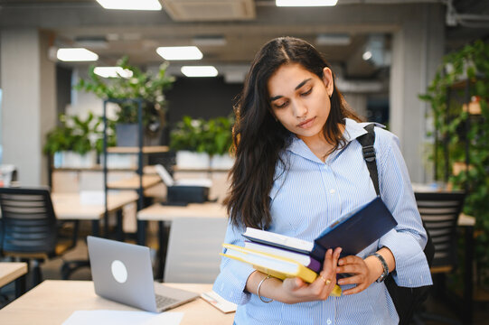 Indian student looking at books in library