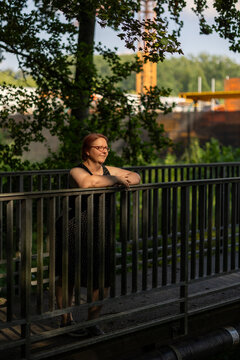 Woman with glasses contemplating on bridge railing in nature