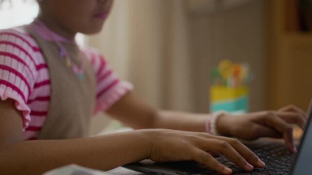 African American child typing on laptop keyboard during online class at home. Footage ideal for promoting e-learning platforms, digital literacy, and modern elementary education