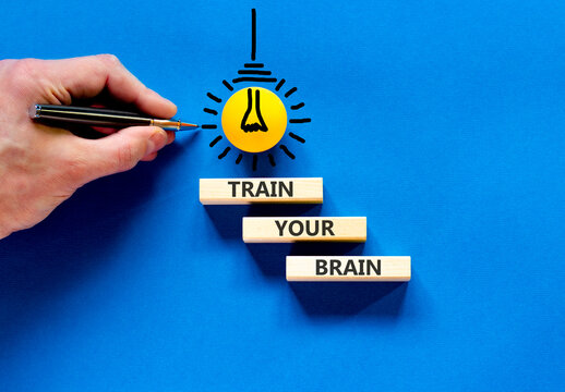 Train your brain words symbol. Concept words Train your brain on beautiful wooden blocks. Beautiful blue background. Businessman hand. Business motivational and train your brain concept. Copy space