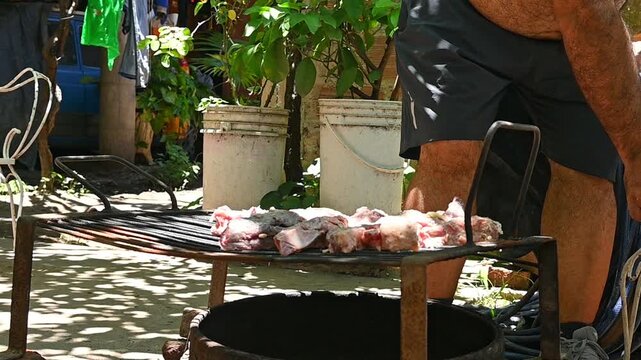 Parrillero acomodando carne vacuna sobre parrilla durante preparaci&oacute;n de asado argentino tradicional