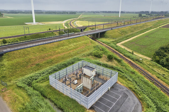 Aerial view of the powergrid transformer for the railway line to Brussels, situated in rural landscape with wind turbines and tracks in Moerdijk, North Brabant, Netherlands.