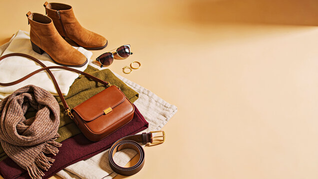 Autumn Women's Clothing Flat Lay with Suede Boots, Leather Bag, Scarf and Accessories on Beige Background