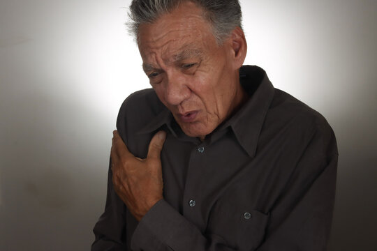 Older Senior Man holding his right shoulder as in pain.