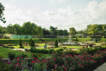 Obraz premium Scenic view of the Sunken Garden at Phillips Park in Aurora, IL featuring formal garden beds, colorful seasonal flowers, manicured hedges, and a central fountain