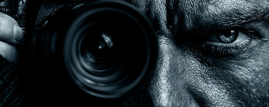 A photographer holding a DSLR camera with a zoom lens 