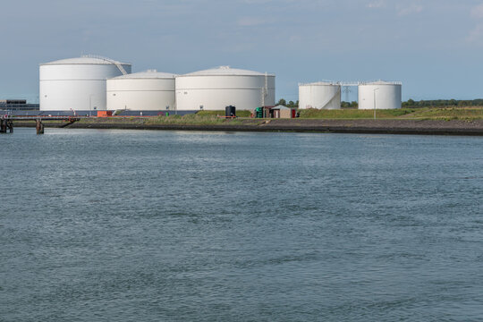 Vlissingen, Netherlands. Large fuel storage tanks for petroleum and biofuels at coastal industrial site with open water foreground