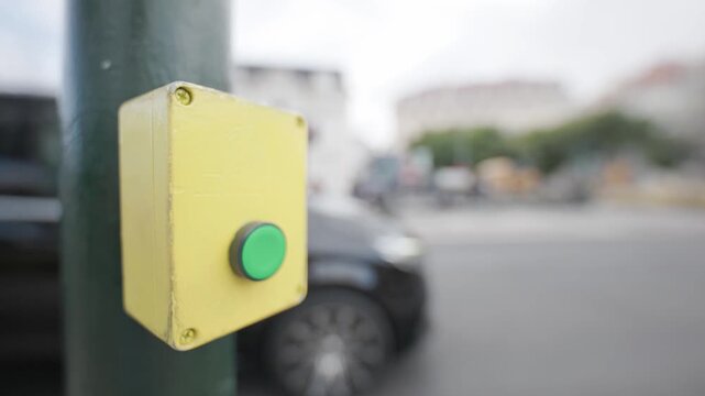 Green pedestrian crosswalk button on a city street crossing