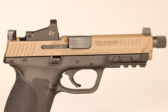 Smith and Wesson MP9 M2.0 9mm Semi-Automatic Pistol with Threaded Barrel, Tan Slide, and Red Dot Optic Mounted on Stand