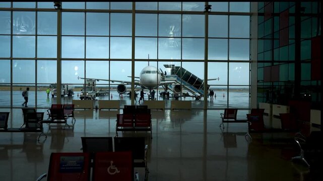 Airplane at gate with boarding stairs at an airport terminal with empty seating area