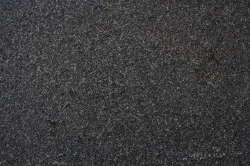 Fototapeta premium Dark grey granite stone creating a rough, granular, and speckled background texture, providing a natural and durable surface
