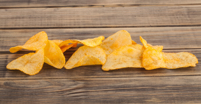 Potato chips on wooden background.