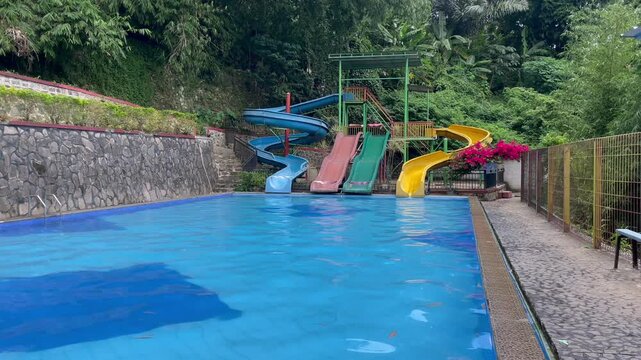 Empty water park with colorful waterslides in the middle of a tropical forest.