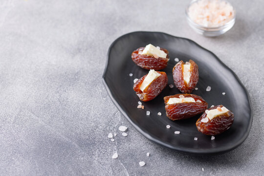 Dates Medjool stuffed with butter and salt on black plate.