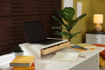 Fototapeta premium Workplace with laptop on riser stand and stationery indoors