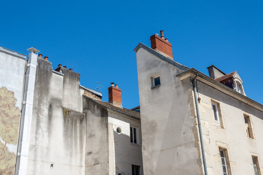 Fa&ccedil;ades anciennes et chemin&eacute;es en briques sous un ciel bleu &eacute;clatant