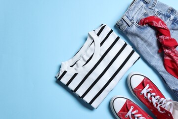 Naklejka premium Stylish women's clothes and shoes on light blue background, flat lay. Space for text