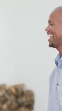 Vertical video: Entering man smiling, laughing at offscreen speaker at home, shirt pen, copy space