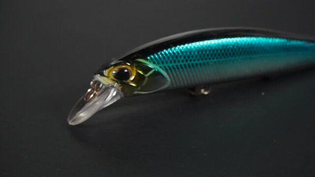 Realistic artificial fishing lure bait moving on dark background