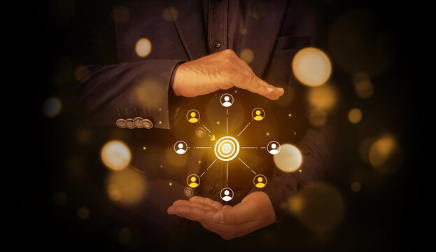 Businessman holding glowing target with connected social network icons in dark background.