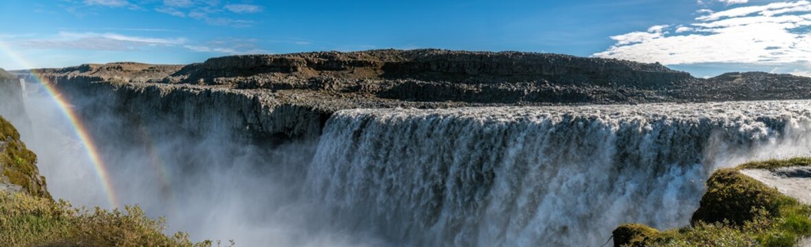 Powerful waterfall with a rainbow in a dark canyon