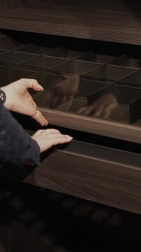 Vertical video. Female hand opening wardrobe drawers with organized storage compartments.