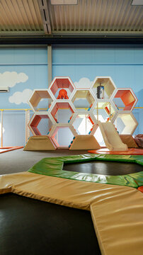 Modern indoor playground with honeycomb climbing structure and trampoline