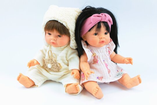 Two Adorable Baby Dolls Sitting Together on White Background &ndash; Cute Toy Dolls with Realistic Faces, Childhood Playtime and Nursery Concept