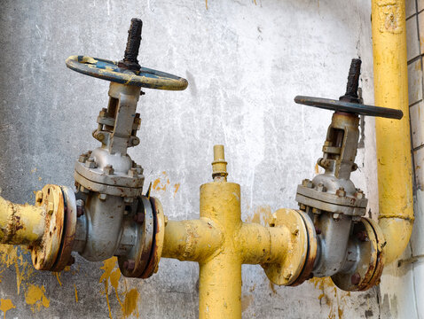Gas pipeline control valves installed on the exterior side of residential housing with yellow utility pipe infrastructure detail