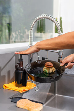 Applying eco friendly dish soap to cast iron skillet for sustainable cleaning