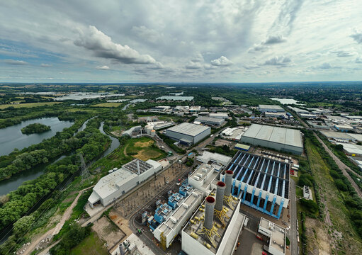 Aerial view of Rye House Power Station with industrial buildings, cooling towers, and surrounding green landscape near the River Lee in Hoddesdon, England, United Kingdom.