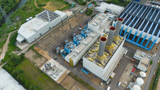 Aerial view of Rye House Power Station featuring industrial chimneys, cooling infrastructure, and power grid facilities surrounded by green landscape in Hoddesdon, England, United Kingdom.