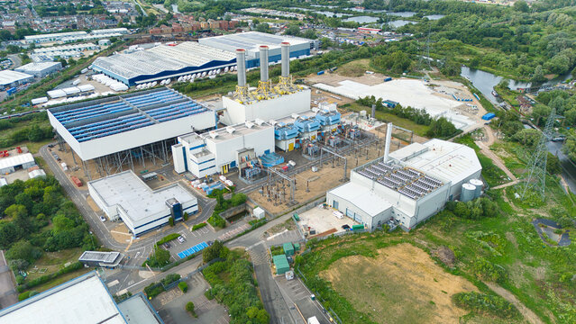 Aerial view of Rye House Power Station featuring industrial chimneys, cooling units, and surrounding green landscape and waterways in Hoddesdon, England, United Kingdom.