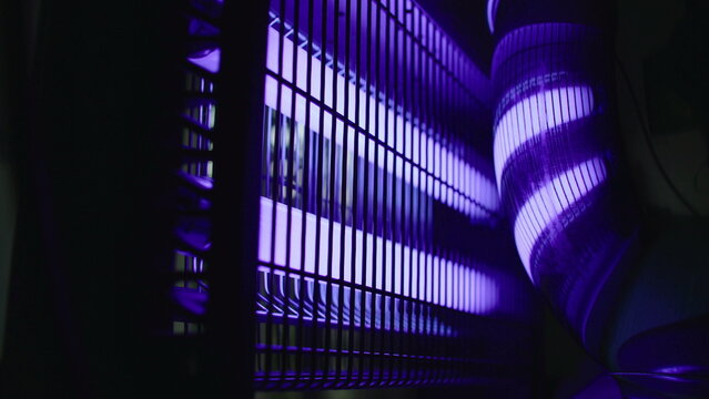 Electric ultraviolet mosquito trap machine with glowing purple tubes inside protective grid designed to attract flying insects and eliminate mosquitoes during warm summer months