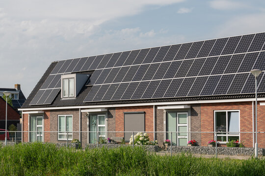 Breskens, Netherlands. Row of residential houses with full rooftop solar panel installations in suburban neighborhood