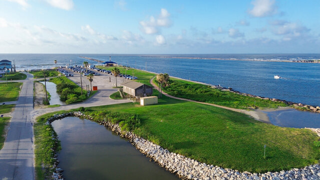 Surfside Jetty County Park offers green spaces public parking adjacent to Brazos River delta. Morning light illuminates quiet coastal paths, rocky shorelines, distant gulf views, Freeport, TX