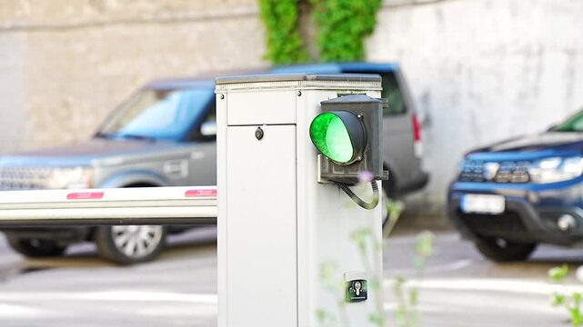 Electronic security boom barrier gate with a bright green passage indicator light symbolizing automated transit verification and urban entry
