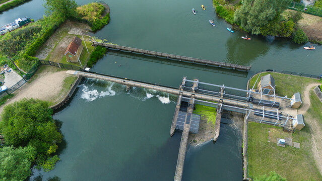 Aerial view of Feildes Weir Lock No.5 on the River Lee with paddleboarders on the water, lush green banks, and historic lock infrastructure in Hoddesdon, England, United Kingdom.