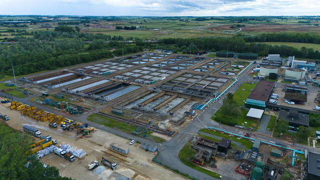 Aerial view of the Alpheus Wastewater Sewage Treatment works featuring large circular sedimentation tanks and rectangular treatment basins in Milton Keynes, England, United Kingdom.