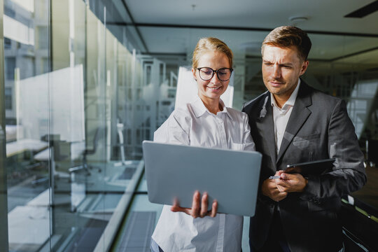 Business professionals collaborate in a modern office, discussing ideas while looking at a laptop screen during daylight hours