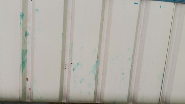 Close up panning shot of a white corrugated metal tin roof ceiling with rusty blue bars