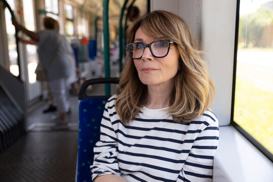 Middle aged woman riding tram in urban setting