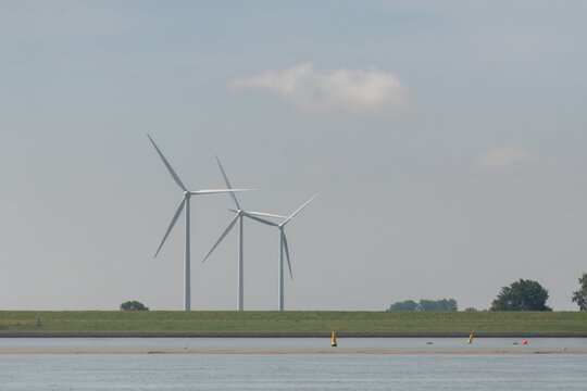 Breskens, Netherlands. Multiple onshore wind turbines along the Westerschelde with navigation buoys illustrating renewable energy and maritime environment