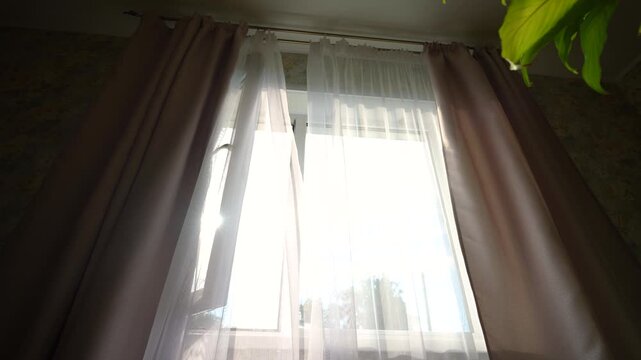 an open window with white curtains fluttering in the wind, the sun's rays fall into the room through the window