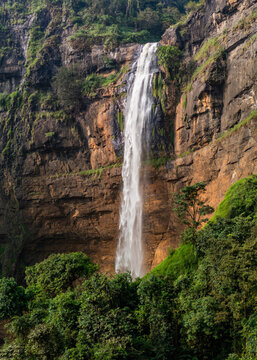 Aerial view of Cikanteh Waterfall cascading down steep rocky cliffs surrounded by lush tropical forest in Geopark Ciletuh, West Java, Indonesia.
