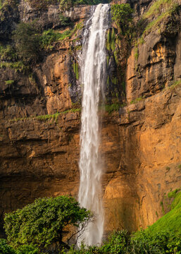 Aerial view of Cikanteh Waterfall cascading down a rugged cliff face surrounded by lush green vegetation in Geopark Ciletuh, West Java, Indonesia.