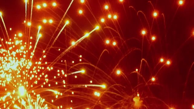 Spectacular fireworks burst into vibrant patterns against the night sky. Golden sparks cascade, creating a dazzling display for Christmas and New Year celebrations.